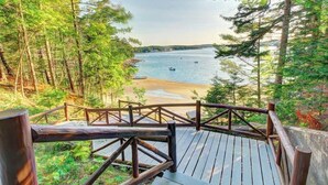 Un pontile in legno con ringhiera che si affaccia su una spiaggia e una zona boschiva.
