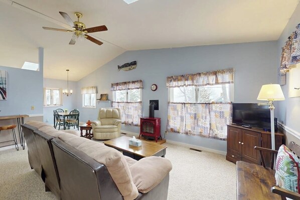 A living room with a sofa, armchair, television, and a fireplace. - Charming Cottage With Ocean Views, Wifi, and Washer and Dryer (Chamberlain)