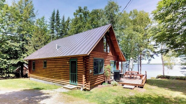 A log cabin with a porch and a deck, surrounded by trees and a lake. - Dog-friendly Lakefront Log Cabin With Peaceful Atmosphere, Dock & Boat Launch (Rockwood)