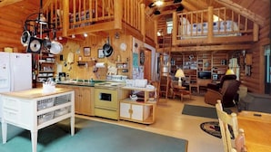 A rustic cabin interior with a kitchen, dining area, and loft space. - Dog-friendly Lakefront Log Cabin With Peaceful Atmosphere, Dock & Boat Launch (Rockwood)