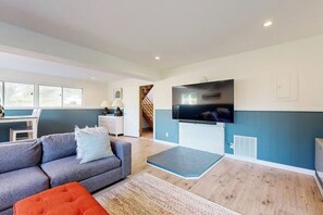 Ein modernes Wohnzimmer mit Sofa, Fernseher und Essbereich mit Tisch und Stühlen.