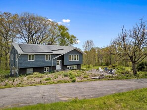 Ein zweistöckiges Haus mit geneigtem Dach, einer Veranda und einer Auffahrt zum Eingang.
