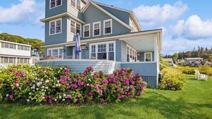 A multi-story house with a porch and a well-maintained garden. - Oceanfront Home Incredible Ocean Views, Deck & Location (East Boothbay)