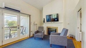 A living room with a fireplace, a television, and two armchairs. - Birch Tree Lane (Bar Harbor)