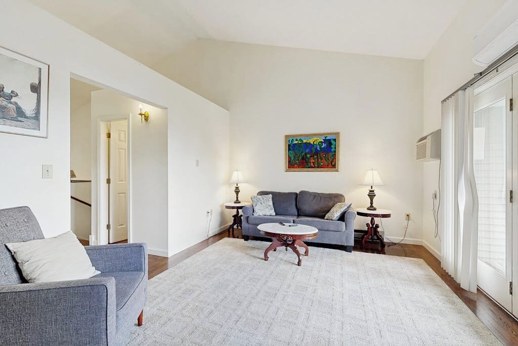 A living room with a sofa, two side tables with lamps, a coffee table, and a painting on the wall.