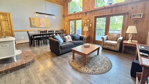 A spacious living area with a high ceiling, wooden walls, and large windows. - Riverfront Home w/ Deck, Amazing Views & Firepit - Near the Best of Maine (Stockton Springs)