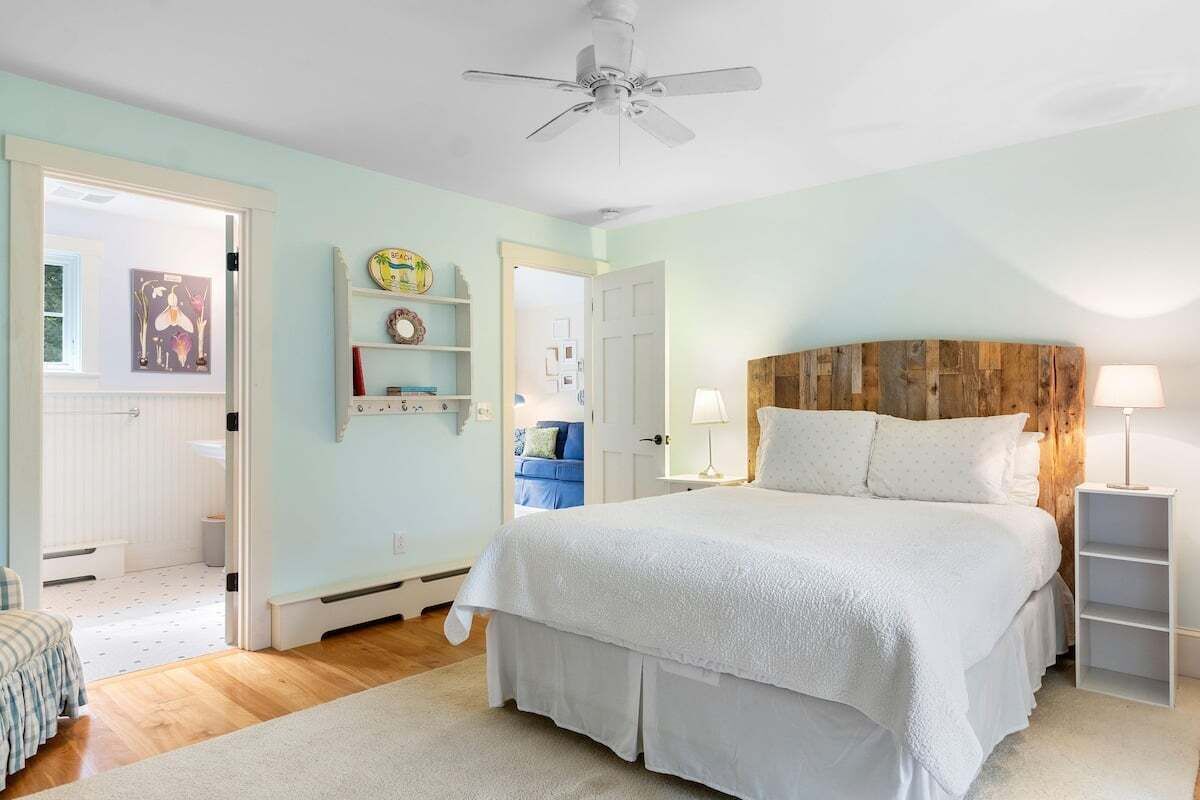 A bedroom with a bed, a ceiling fan, a wooden headboard, and a bedside lamp.
