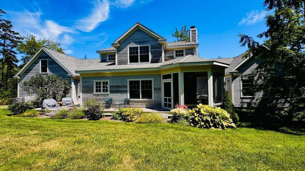 A two-story house with a porch, a garage, and a well-maintained lawn.