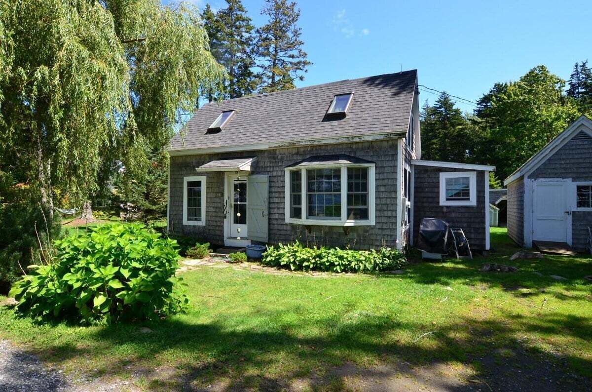 A two-story house with a front porch, a garage, and a small attached shed.