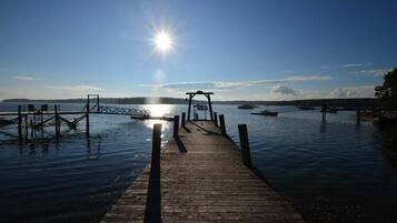 A wooden pier leading to a dock with boats in the background.