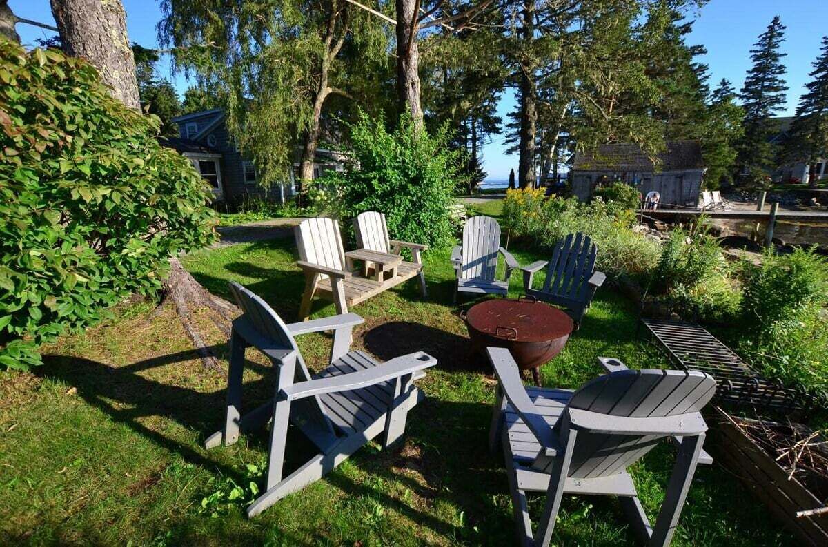 A patio area with Adirondack chairs, a fire pit, and a view of a lake.