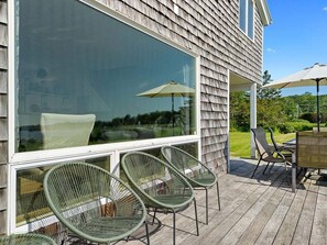 Una terraza con mobiliario exterior, incluyendo sillas y una mesa, y un ventanal grande.