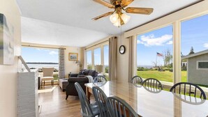 A spacious dining area with a large table and chairs, a ceiling fan, and a view of the outdoors. - Owls Nest on Crescent Beach (Owls Head)