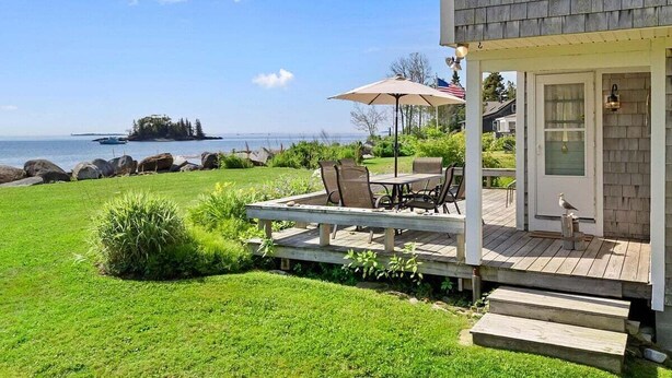A house with a deck, outdoor seating, and a view of the ocean. - Owls Nest on Crescent Beach (Owls Head)
