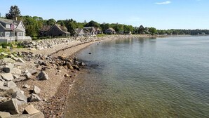 A lakeside property with a rocky shoreline, houses with gabled roofs, and a clear view of the water. - Owls Nest on Crescent Beach (Owls Head)