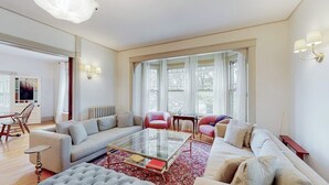 A spacious living room with a sofa set, a glass coffee table, and a red patterned rug. - Beautiful Home With Ping-pong, Fast Wifi & W/D - Walk to Dining (Wiscasset)