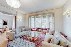 A spacious living room with a sofa set, a glass coffee table, and a red patterned rug. - Beautiful Home With Ping-pong, Fast Wifi & W/D - Walk to Dining (Wiscasset)