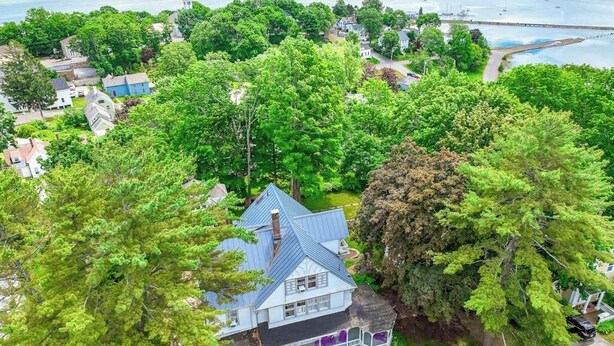 A house surrounded by dense trees, with a view of a body of water and a bridge in the background. - Beautiful Home With Ping-pong, Fast Wifi & W/D - Walk to Dining (Wiscasset)