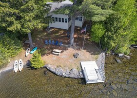 A cabin with a dock, kayaks, and a picnic table.