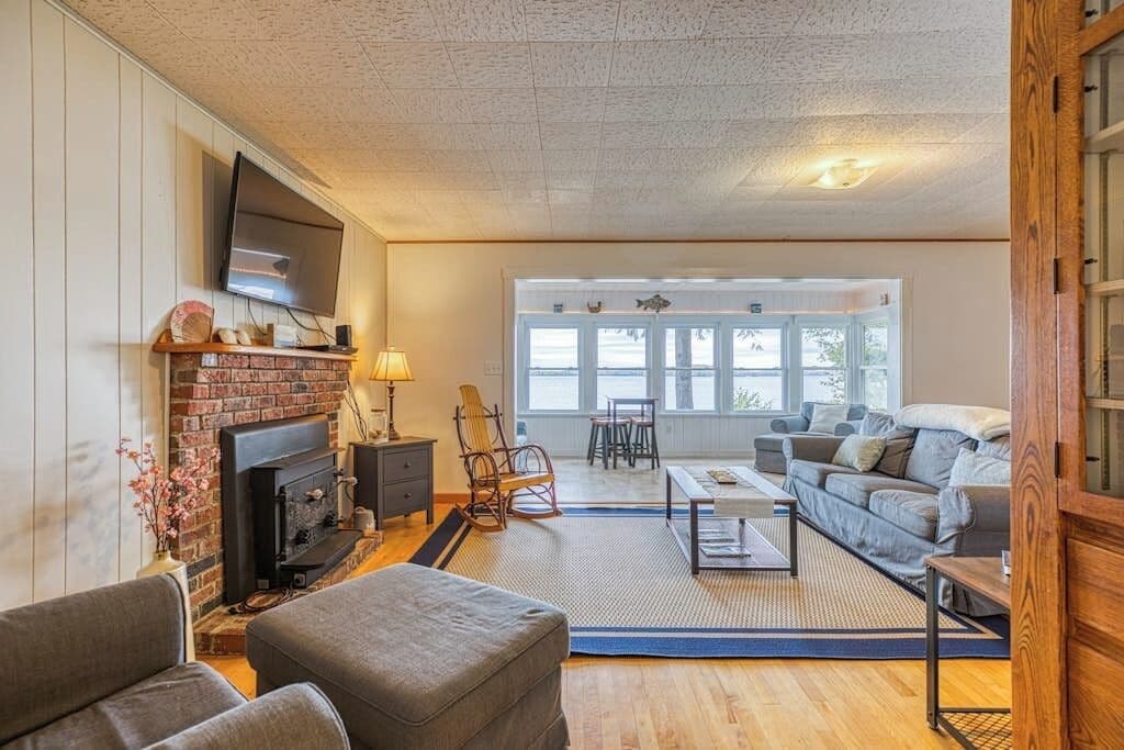 A living room with a fireplace, a sofa, a TV, and a large window.