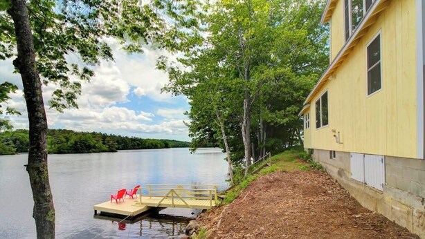 A lakeside property with a dock, a yellow building, and a forested area. - Newly Restored Waterfront Cottage With Private Dock, Fireplace, & Farm - Dogs OK (Newcastle)