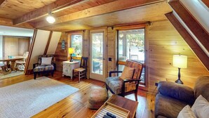 Una habitació acollidora amb terres de fusta, una taula de menjador, cadires, un sofà i una làmpada.