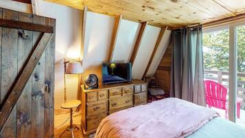 A bedroom with a bed, a dresser, a TV, and a window with curtains.