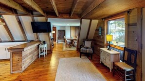 Un interior de fusta amb zona de menjador, televisió i finestra.