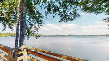 A wooden deck overlooking a calm lake with trees and distant hills.