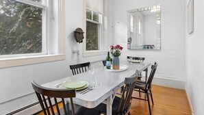 A dining area with a white table, chairs, and a vase with flowers.