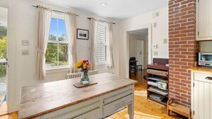 A room with a wooden table, a brick column, and a view of the outdoors. - Beauchamp Cottage, Near Rockport Harbor and Golf c (Rockport)