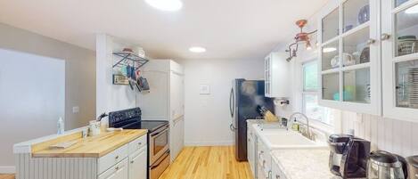 A compact kitchen with white cabinetry, a wooden floor, and a built-in oven.