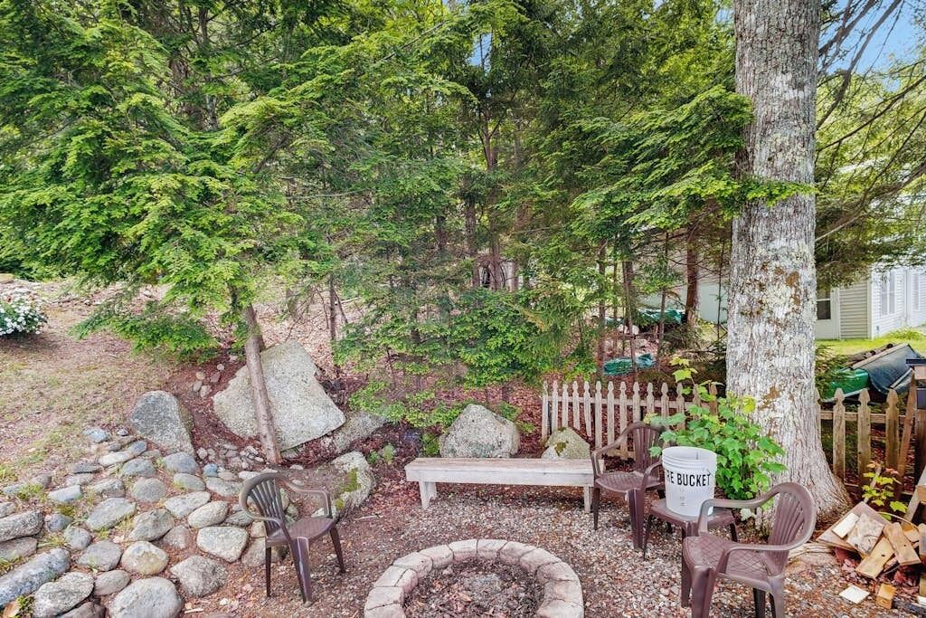 A garden with a fire pit, seating area, and a wooden fence.