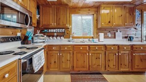 Een houten keukentje in chaletstijl, met een groot fornuis, oven en magnetron.