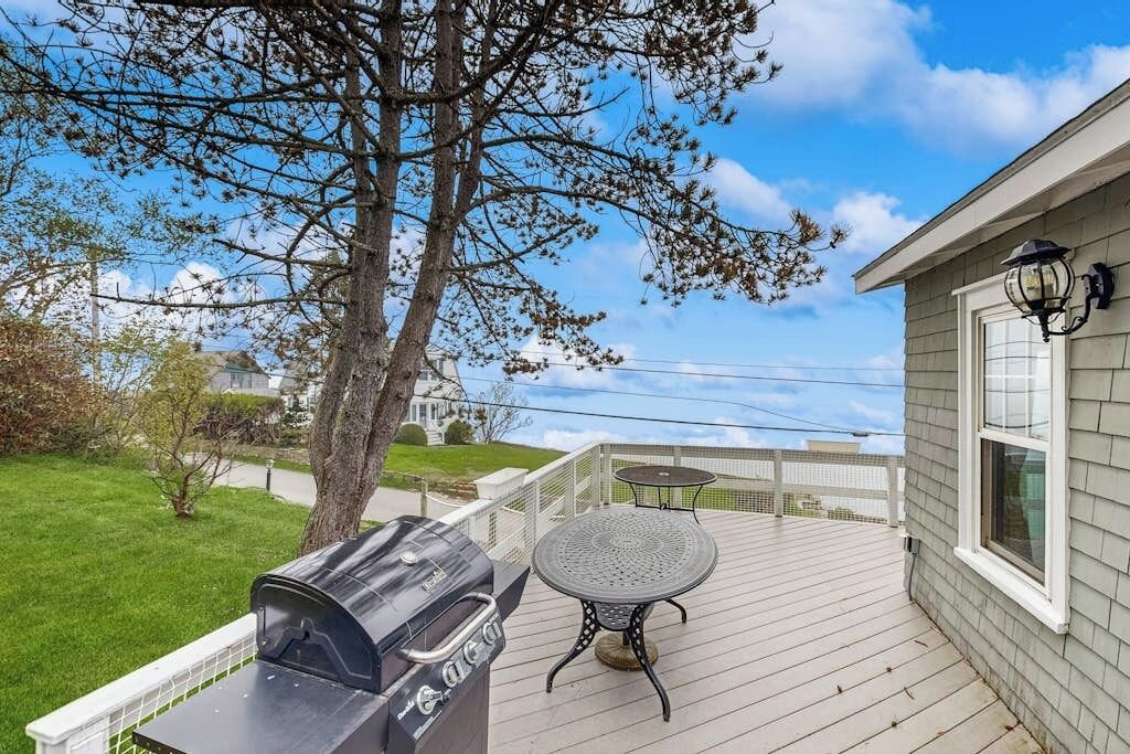 Une terrasse avec un barbecue, une table et une lampe.