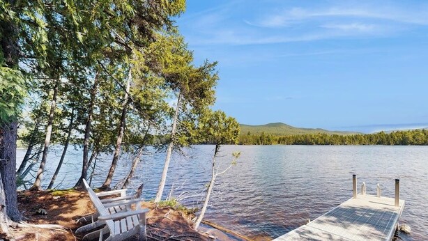 A lakeside dock with a bench and a small boat. - Dog-friendly Lakefront Home With Deck, Grill, Wifi, Shared Dock & Water Access (Greenville)