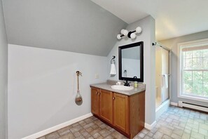 A bathroom with a wooden vanity, a sink, a mirror, and a towel rack. - Peaceful Home With Forest Views & Great Yard - Minutes to Town (Wiscasset)