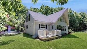 A single-story house with a porch, a fenced yard, and trees. - Peaceful Home With Forest Views & Great Yard - Minutes to Town (Wiscasset)
