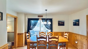 A dining room with a wooden table and chairs, a chandelier, and a view of a dock with a boat. - Lake & Trail Landing- ATV & Snowmobile Access (Greenville)