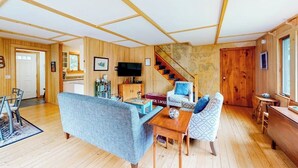A wooden interior with a sofa, a coffee table, a TV, and a staircase. - Cobb Nob (Southwest Harbor)