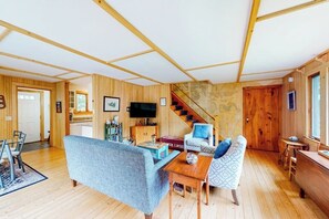 A wooden interior with a sofa, a coffee table, a TV, and a staircase. - Cobb Nob (Southwest Harbor)