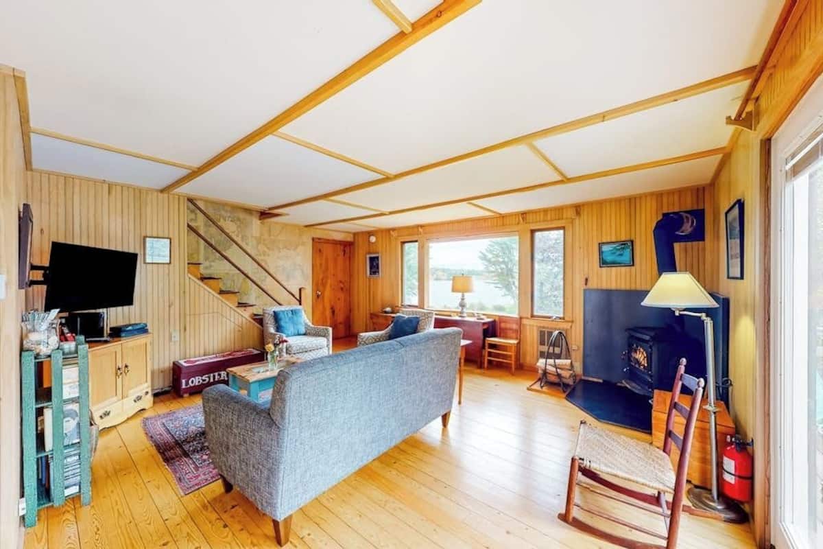 A wooden interior with a sofa, TV, fireplace, and a staircase.