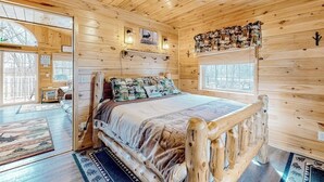 A wooden cabin interior with a bed, wooden walls, a window, and a wall-mounted shelf. - Lake-view Two-story Home With Beach Access, Wood Stove, Grill, W/d, & Fast Wifi (Greenville Junction)