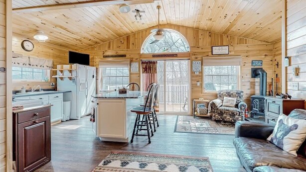 A cabin interior with a kitchen, dining area, and living room. - Lake-view Two-story Home With Beach Access, Wood Stove, Grill, W/d, & Fast Wifi (Greenville Junction)