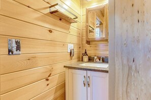 A wooden interior with a sink, cabinets, and a mirror. - Lake-view Two-story Home With Beach Access, Wood Stove, Grill, W/d, & Fast Wifi (Greenville Junction)