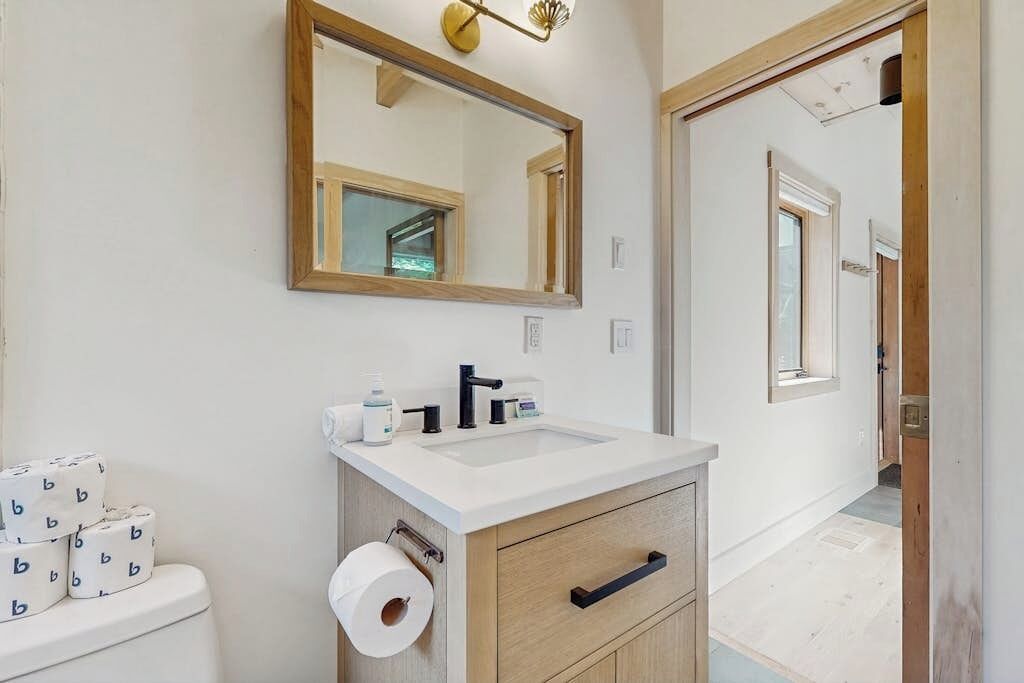 Een badkamer met toilet, wastafel, spiegel en een rol wc-papier.