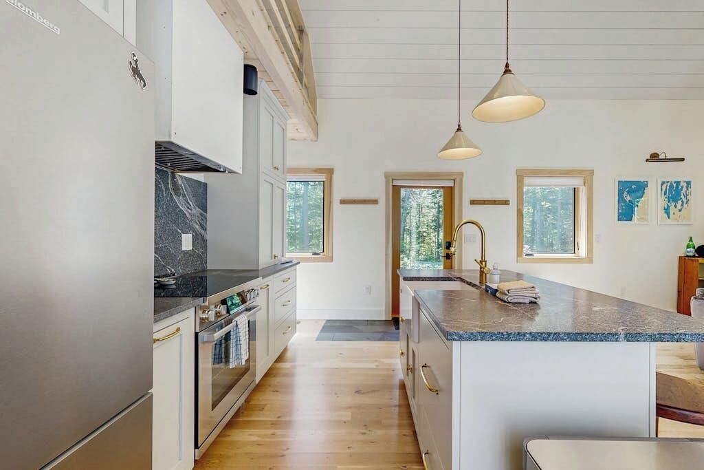 A modern kitchen with a central island, stainless steel appliances, and pendant lighting.