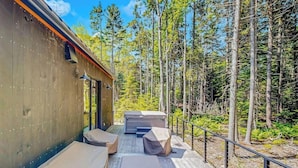 A cabin with a deck, two covered benches, and a hot tub. - Charming New Home With Hot Tub, Spacious Deck, Gas Grill, Wifi, and Washer/dryer (East Boothbay)