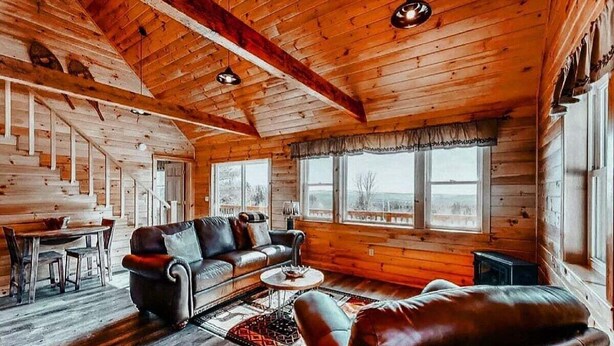 Ein Holzblockhaus-Interieur mit einer Couch, einem Couchtisch und einem Essbereich.