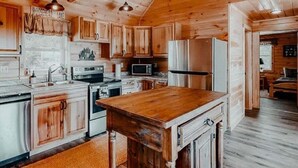 Ein Holzhaus-Interieur mit Küche, Essbereich und sichtbarem Schlafzimmer.